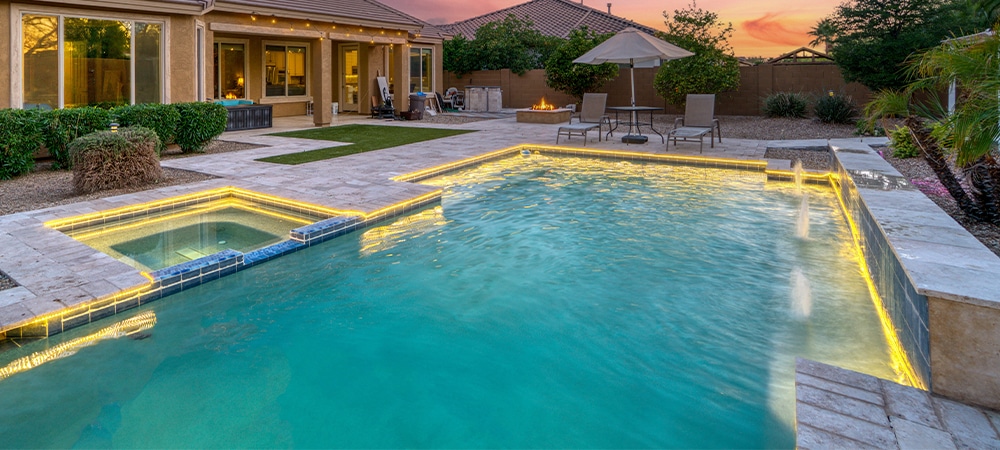 landscaping around swimming pool, hardscape, paver patio, lightening in pool, pool waterfall
