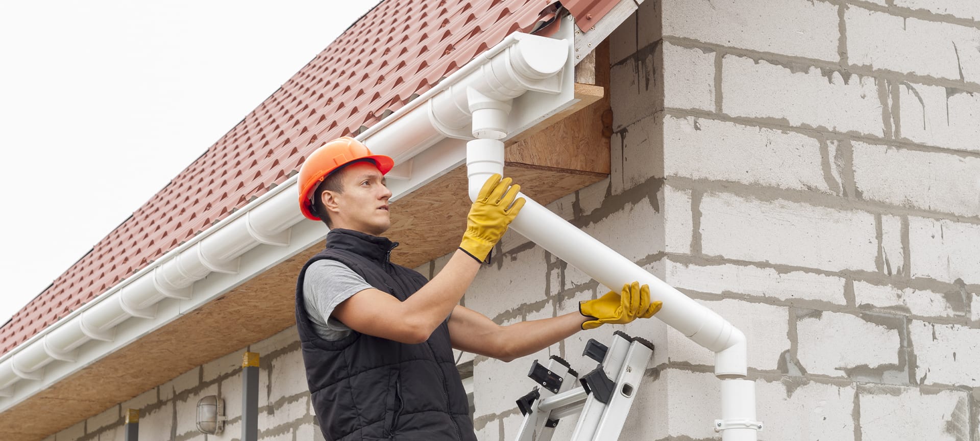 construction worker installs the gutter system on the roof