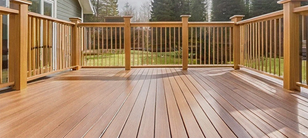 TimberTech brown composite deck with railing and tree-filled background on a sunny day
